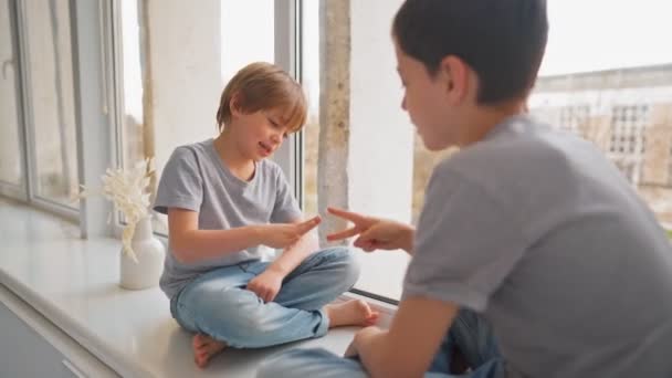 Vrienden spelen naar Rock Paper Schaar spel op vensterbank. Broeders spelen naar Rock Paper Schaar spel. — Stockvideo