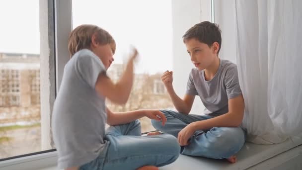 Vrienden spelen naar Rock Paper Schaar spel op vensterbank. Broeders spelen naar Rock Paper Schaar spel. — Stockvideo