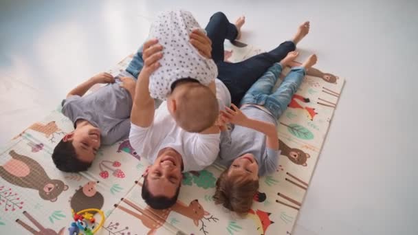 リビングルームで床で笑顔の家族。床の上にカメラをポーズしている子供たちと一緒に大きな幸せな家族 — ストック動画