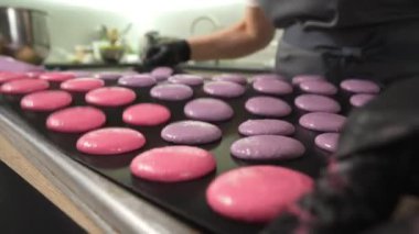 Evde badem kurabiyesi yapma süreci. Kadın pasta şefinin elinde ganache ve torbadan sıkılmış kırmızı meyve reçeli tutan el resimleri. Doğa çörekleri.