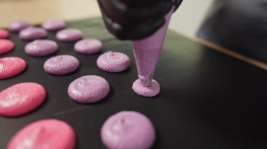 Evde badem kurabiyesi yapma süreci. Kadın pasta şefinin elinde ganache ve torbadan sıkılmış kırmızı meyve reçeli tutan el resimleri. Doğa çörekleri.