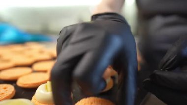 Evde badem kurabiyesi yapma süreci. Kadın pasta şefinin elinde ganache ve torbadan sıkılmış kırmızı meyve reçeli tutan el resimleri. Doğa çörekleri.