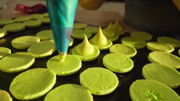 Proces výroby makarónů doma. Fotka ženských rukou šéfkuchařky, držící bílý macaron s ganache a mačkající červený ovocný džem z tašky. Přírodní pečivo makarony — Stock video
