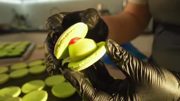 Process Of Making macaroon at home. Shot of hands of female pastry chef holding white macaron with ganache and squeezing red fruit jam from bag. Nature pastry macaroons — Stock Video