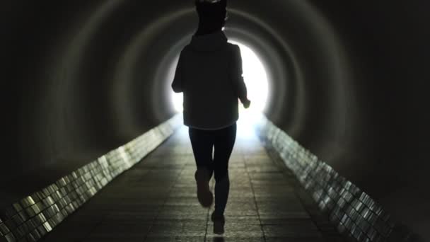 Постріл жінки біжить через освітлений тунель — стокове відео