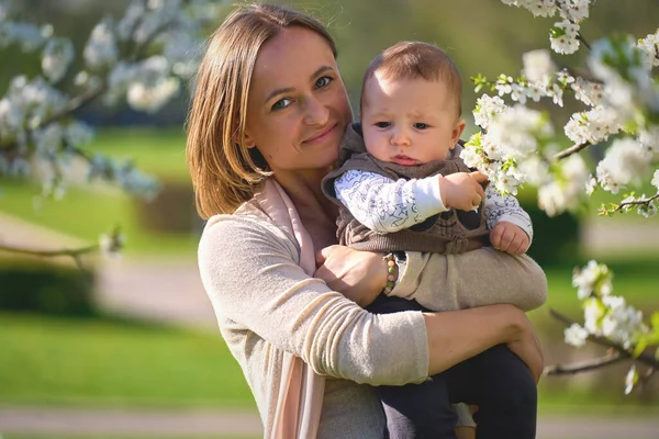 Donna con un bambino in un giardino fiorito. Famiglia in giardino primaverile — Foto Stock