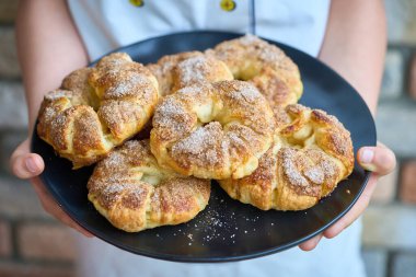 Elinde ev yapımı keklerle tabak tutan bir çocuk..