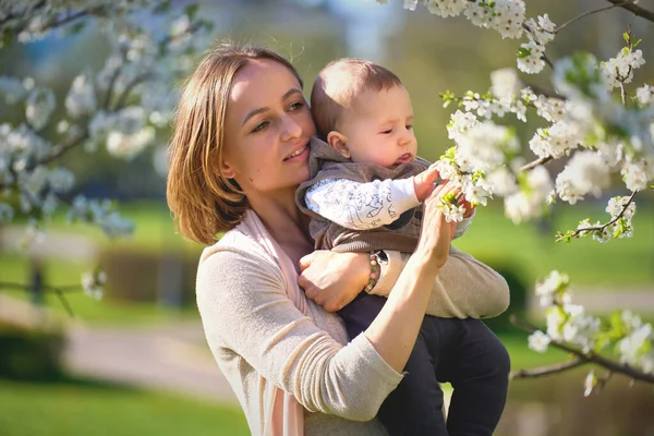 Donna con un bambino in un giardino fiorito. Famiglia in giardino primaverile — Foto Stock