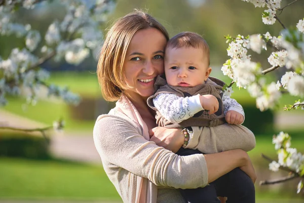 Donna con un bambino in un giardino fiorito. Famiglia in giardino primaverile — Foto Stock