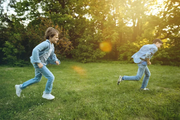 Два брата бегут на улицу в парке на закате — стоковое фото