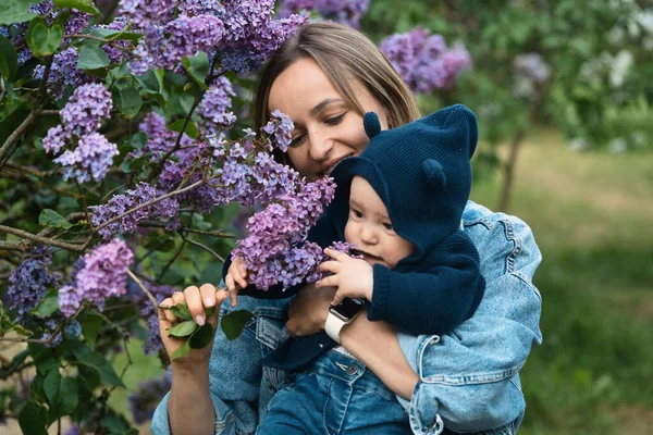 Счастливая мать и сын в саду цветущей сирени — стоковое фото