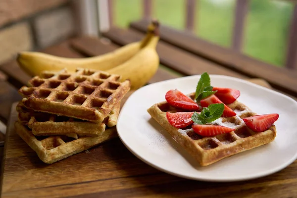 Nahaufnahme des Frühstücks belgische Waffeln mit Erdbeere und Banane mit Minze auf Holzgrund — Stockfoto