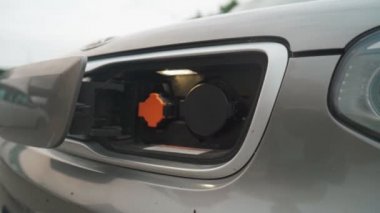 EV pili şarj etmek için elektrik kablosunu elektrikli bir arabaya bağlayan adam. Elektrikli bir arabayı şarj ediyorum. Erkek el şarj istasyonunun prizine dokunuyor.