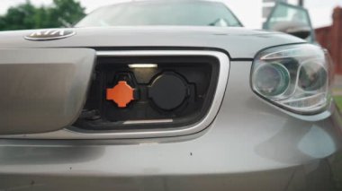 EV pili şarj etmek için elektrik kablosunu elektrikli bir arabaya bağlayan adam. Elektrikli bir arabayı şarj ediyorum. Erkek el şarj istasyonunun prizine dokunuyor.