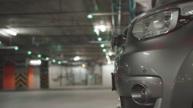 EV pili şarj etmek için elektrik kablosunu elektrikli bir arabaya bağlayan kadın. Elektrikli bir arabayı şarj ediyorum. Bir kadın eli şarj istasyonunun prizine dokunur.