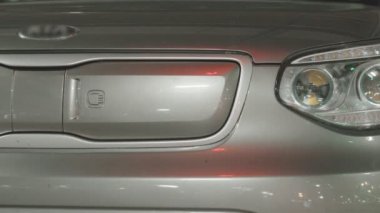 EV pili şarj etmek için elektrik kablosunu elektrikli bir arabaya bağlayan kadın. Elektrikli bir arabayı şarj ediyorum. Bir kadın eli şarj istasyonunun prizine dokunur.