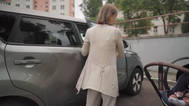 Jeune mère mettant bébé dans le siège d'auto sécurisation de l'enfant pour le voyage en voiture parent responsable s'occupant de la sécurité des tout-petits dans le véhicule — Video