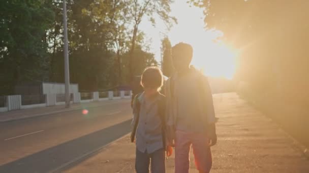 Les écoliers rentrent de l'école au coucher du soleil. — Video