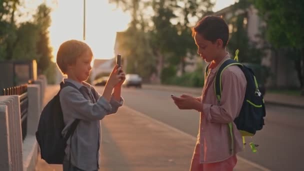 Dwoje dzieci blogerzy nagrywa bloga na smartfonie na ulicy. — Wideo stockowe