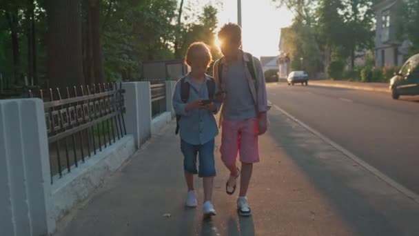 Skolpojkarna återvänder från skolan om en solnedgång.. — Stockvideo