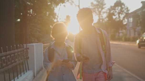 Los colegiales regresan de la escuela al atardecer. — Vídeo de stock