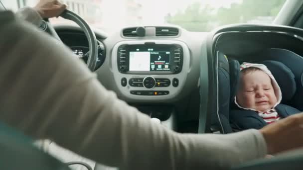 Mother driving car with her baby in car seat. — Stock Video