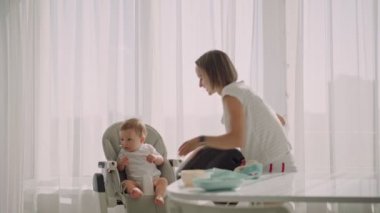  Mother puts the child in a feeding chair. Feeding the baby