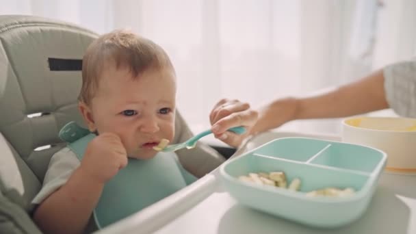 Les parents nourrissent l'enfant avec des tranches de banane. La première nourriture complémentaire de l'enfant — Video