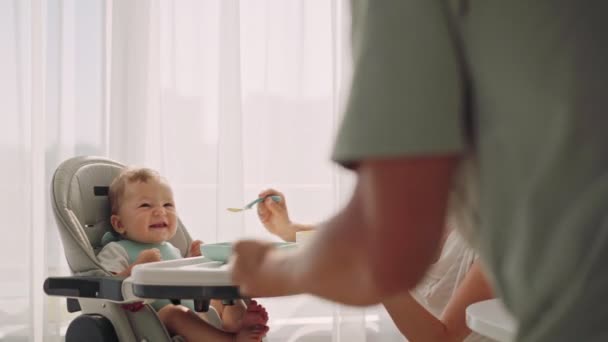 Батько розважає дитину під час їжі. Батько жонглює, поки мати годує дитину. Погодувати дитину. — стокове відео