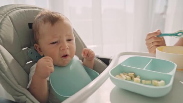 A szülők banánszeletekkel etetik a gyereket. A gyermek első kiegészítő étele — Stock videók