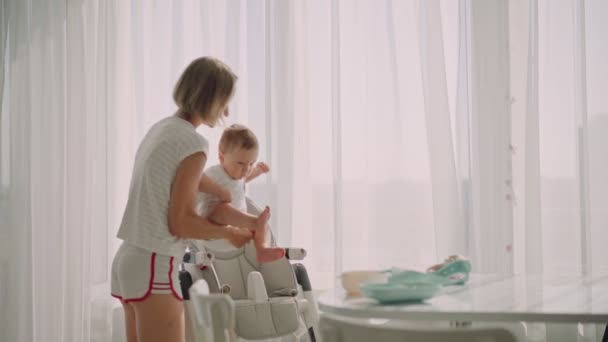 Mother puts the child in a feeding chair. Feeding the baby — Vídeo de Stock