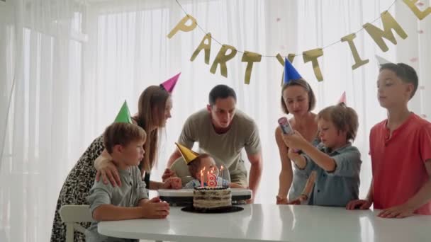 Feliz familia joven con amigos celebra el cumpleaños de un niño de 8 meses. El primer año de vida. Fiesta en casa — Vídeo de stock