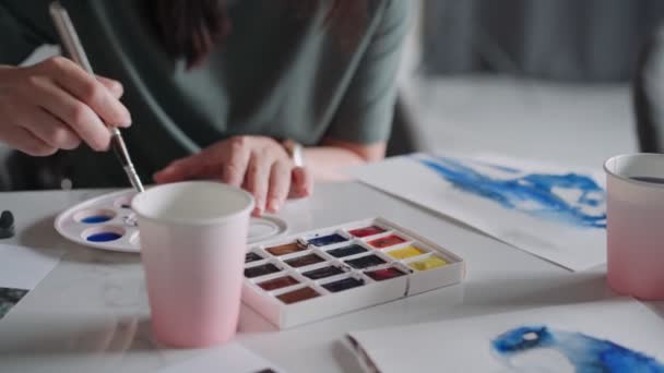 Lähikuva naispuolisista käsistä piirtämässä papukaijaa paperiarkille eri väreissä. Pysy kotona, pelikonsepti. Master luokan piirustus — kuvapankkivideo