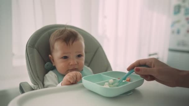 Eltern füttern ihr Kind mit Bananenscheiben. Die erste ergänzende Nahrung des Kindes — Stockvideo