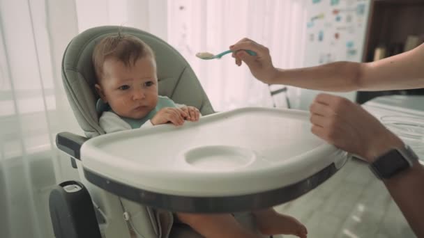 Eltern füttern ihr Kind mit Bananenscheiben. Die erste ergänzende Nahrung des Kindes — Stockvideo