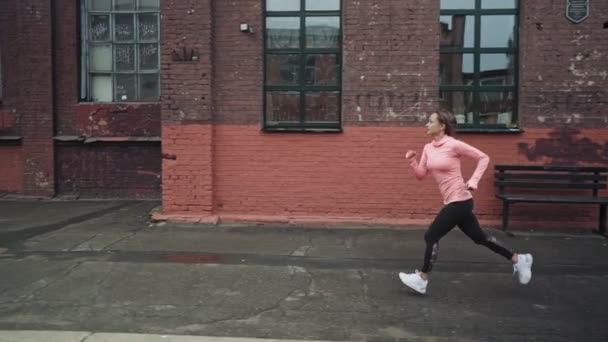 Eine junge Frau läuft auf einer Straße des alten Stadtbezirks. Rückansicht. Auf dem Weg zum Erfolg und zum Erreichen von Zielen. Kontrastschuss. — Stockvideo