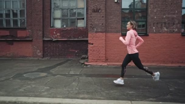 Egy fiatal nő rohangál a régi városrész utcájában. Visszanézni. Úton a siker és a célok elérése felé. Kontrasztlövés. — Stock videók