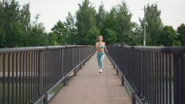 Zdolna młoda, kaukaska kobieta biegająca rano w zwolnionym tempie po moście. Koncepcja zdrowego stylu życia. Dalekie szanse na ucieczkę. Witalność sportu. — Wideo stockowe