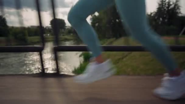 Vista de cerca de los pies femeninos corriendo por una carretera asfaltada hacia el atardecer — Vídeos de Stock