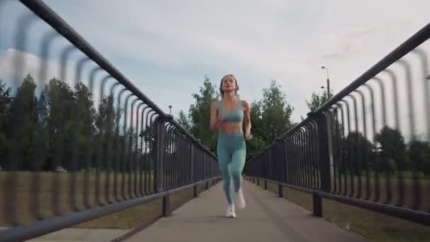 아침에 다리 위를 열심히 달리고 있는 건강 한 젊은 코카서스 여성. 건강 한 생활 방식에 대한 개념. 달리기 하는 여자의 긴 샷. 운동의 활력. — 비디오
