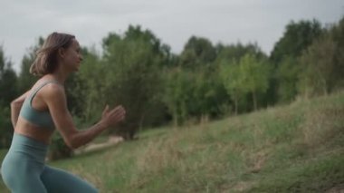 Ağır çekimde koşan genç bir kadın. Genç ve formda bir kadın kardiyo egzersizi yapıyor. İlerleme kavramı. Orta çekim.