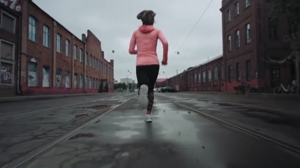 Une jeune femme qui court le long d'une vieille rue de quartier. Vue de derrière. Sur le chemin du succès et de l'atteinte des objectifs. Plan contrasté. — Video