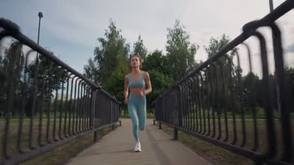 朝、橋の上を走っている若い白人女性が集中的に走っていた。健康的なライフスタイルの概念。逃走中の女のロングショット。スポーツの活力. — ストック動画