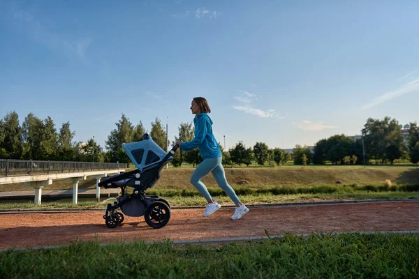 Aktywny jogging matki. Jogging lub power walking kobieta z wózkiem dla dzieci rano. Matka z dzieckiem w wózku uruchomiony. — Zdjęcie stockowe