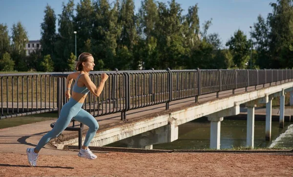 Mooie vrouwelijke jogger loopt in de ochtend over brug. — Stockfoto