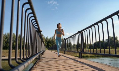 Güzel bayan koşucu sabah köprüde koşuyor..