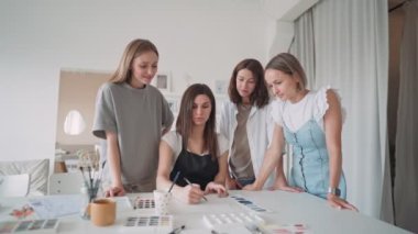 Sanat atölyesindeki dört güzel beyaz kadının ön görüntüsü. Genç bir öğretmen resim dersi veriyor.