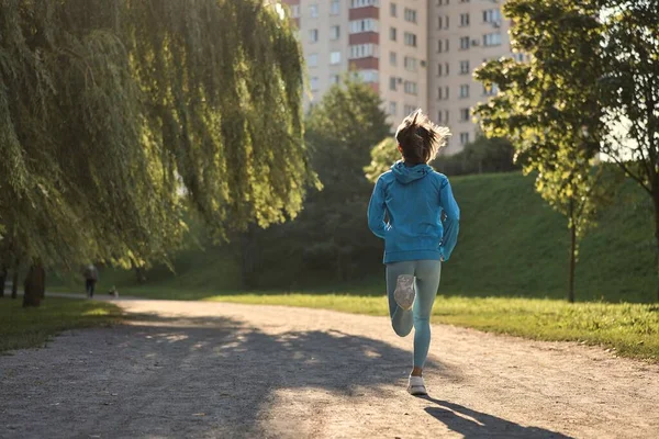 Jonge atletische vrouw joggen op de weg in de ochtend — Stockfoto