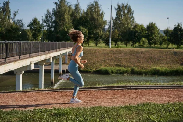 Jonge atletische vrouw joggen op de weg in de ochtend — Stockfoto