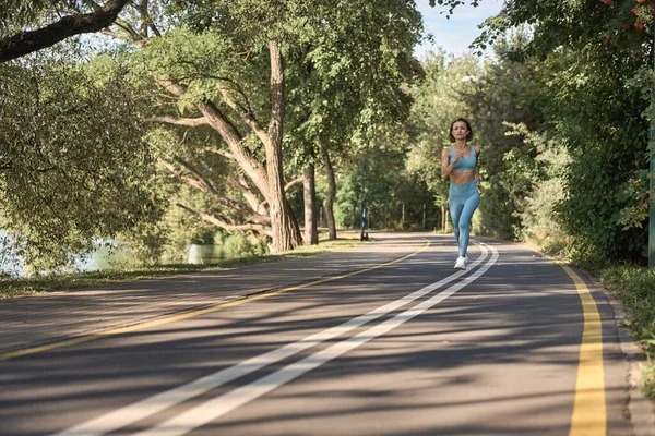 Jonge atletische vrouw joggen op de weg in de ochtend — Stockfoto